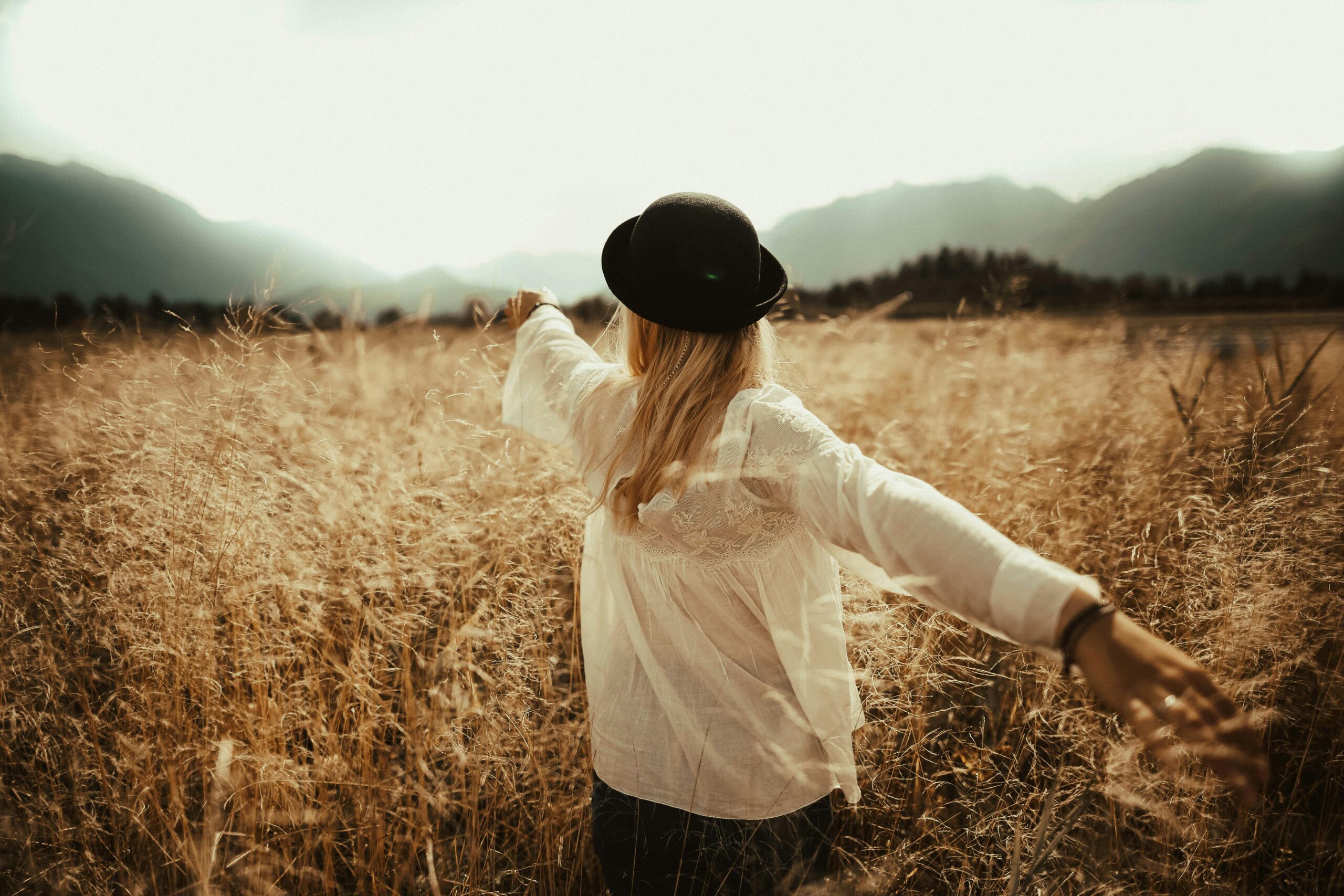 A woman in a field, arms outstretched, enjoying a peaceful autumn day.